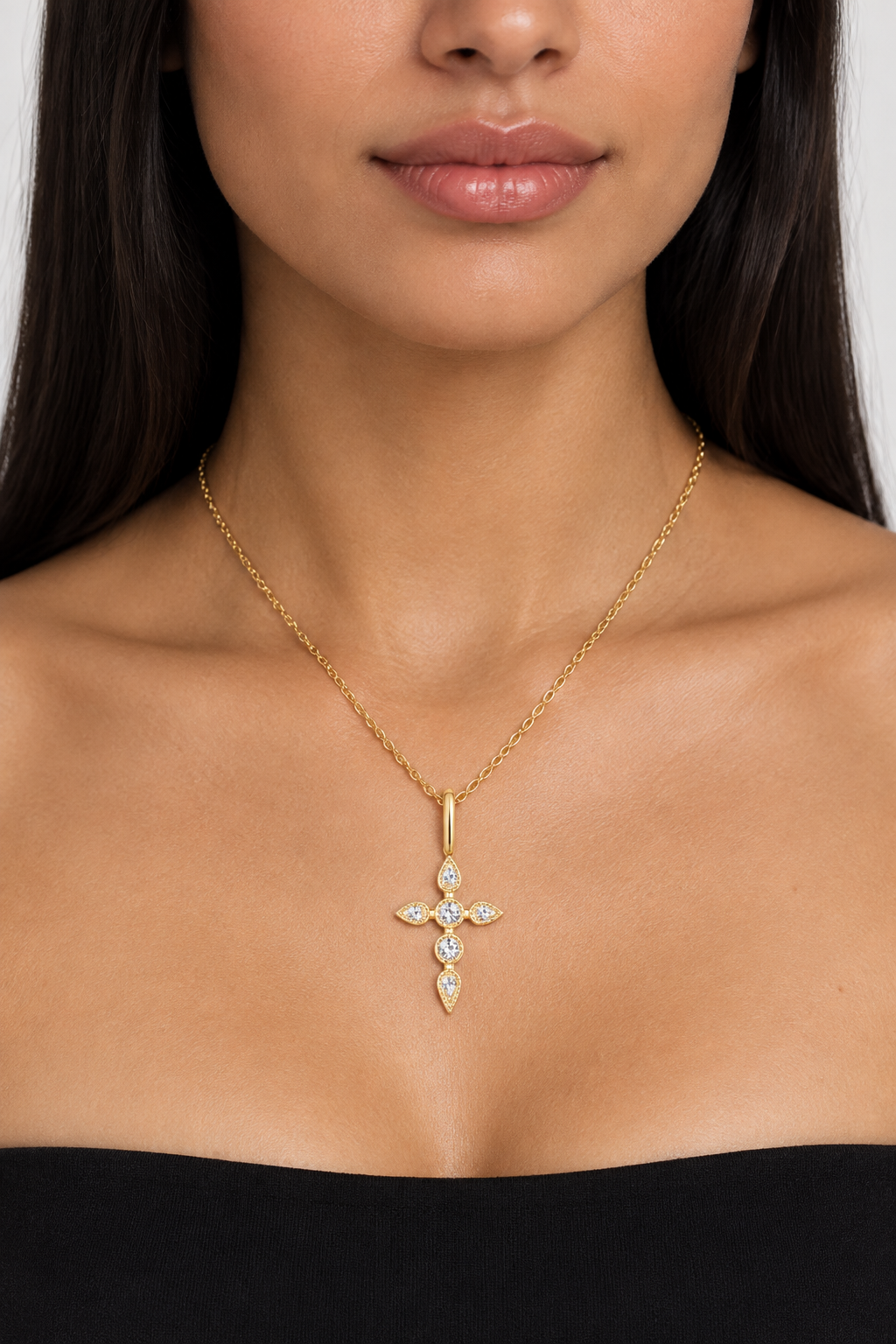Modelo a usar colar dourado com pendente de cruz e pedras transparentes